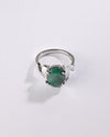 Silver ring with a green gemstone on a light gray background